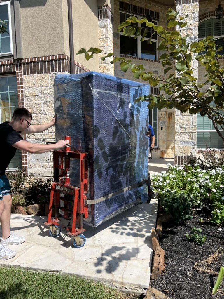 Tera Moving crew moving a wrapped gun safe on a heavy-duty dolly at a Houston home